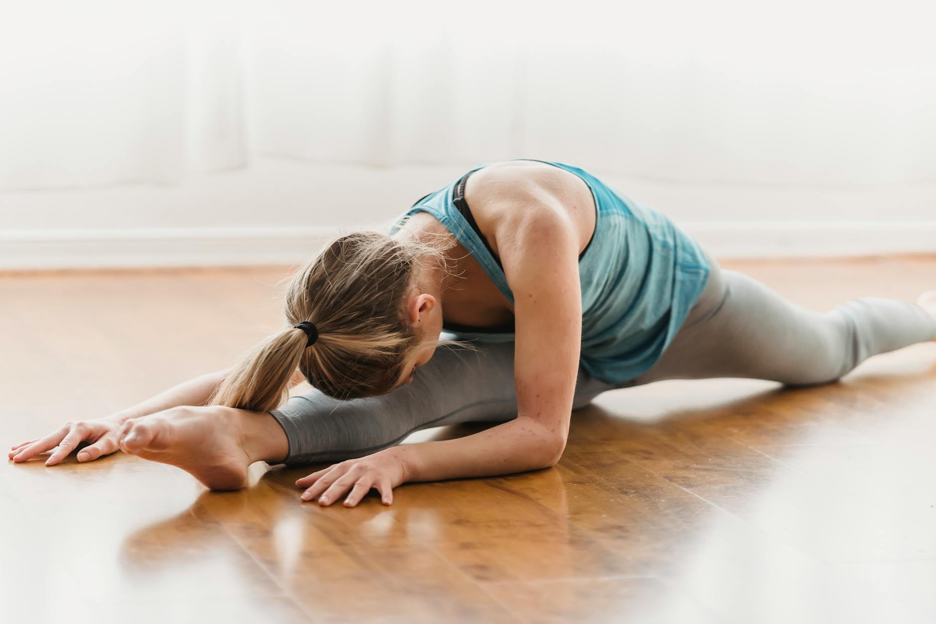 flexible woman doing split while warming up on floor
